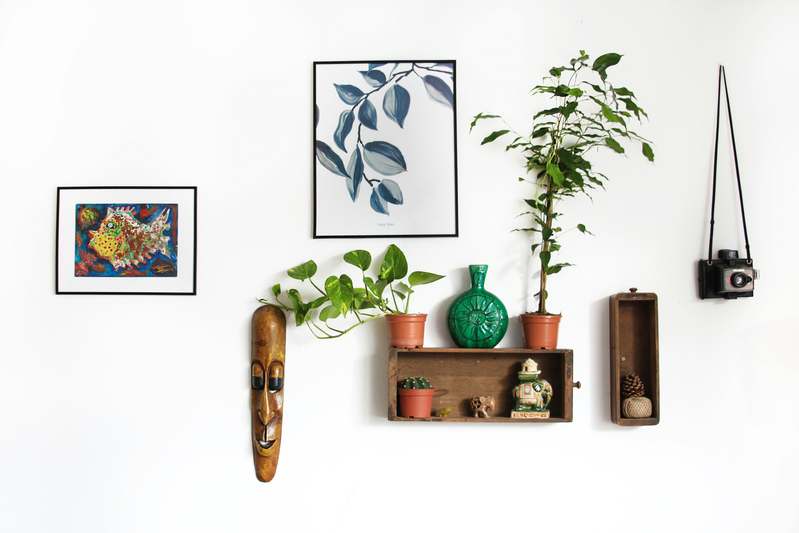 A clutter-free workbench with wooden shelving, woven baskets, paintbrushes, and a half-finished macramé wall hanging